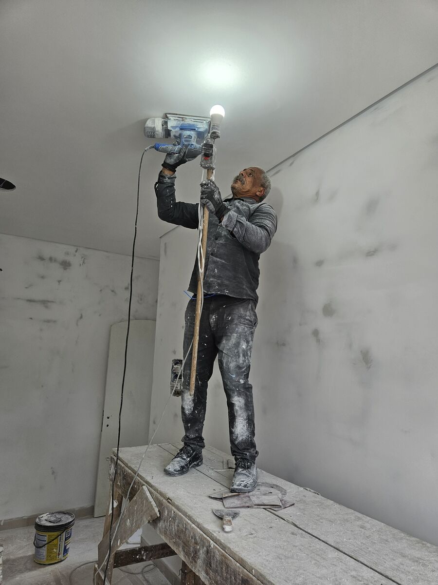 Lixamento de parede com máquina e foco de luz direto no local